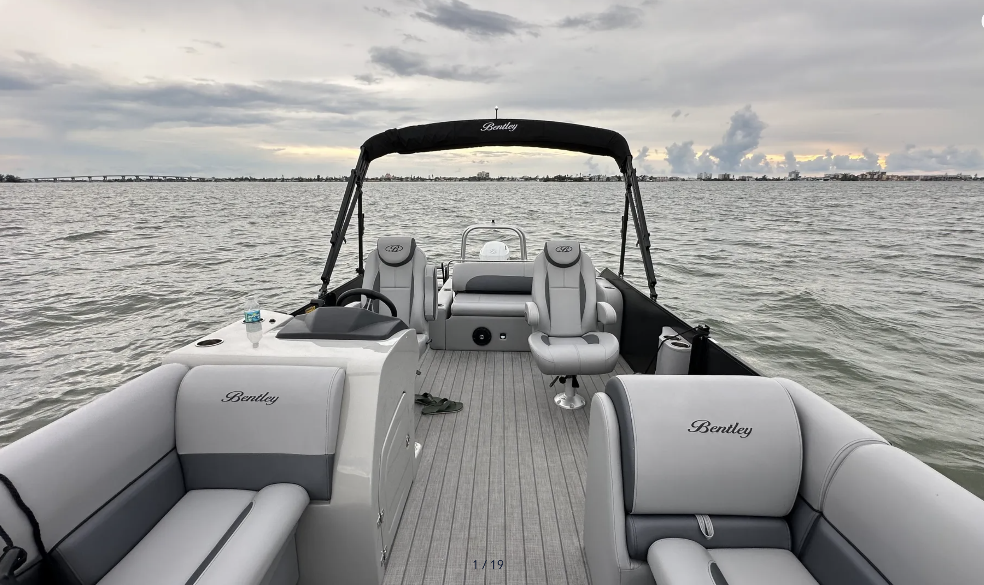 Bentley tritoon interior showing the helm, captain’s chairs, seating, and open water