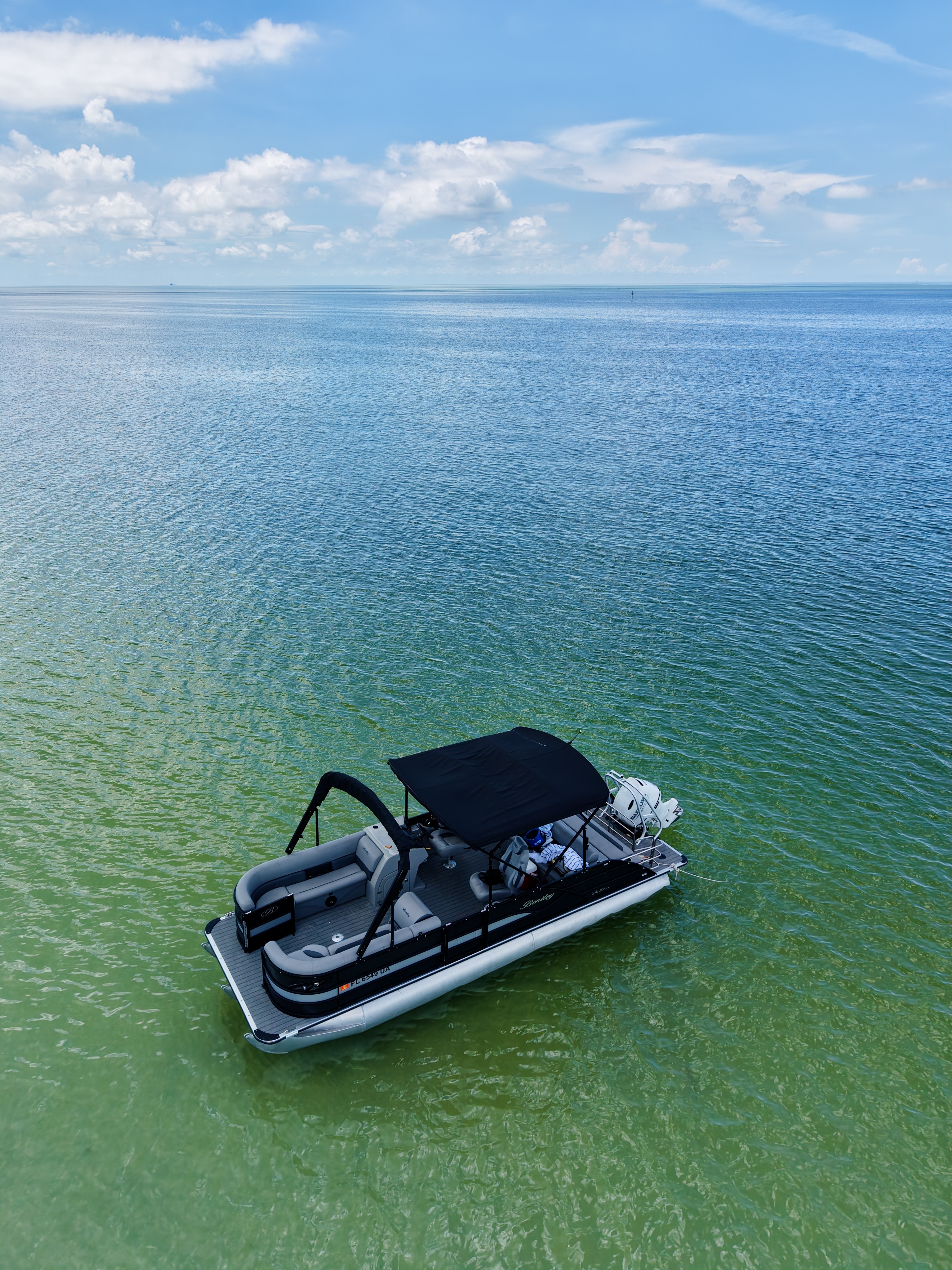Aerial portrait view of the Bentley tritoon cruising over clear coastal water