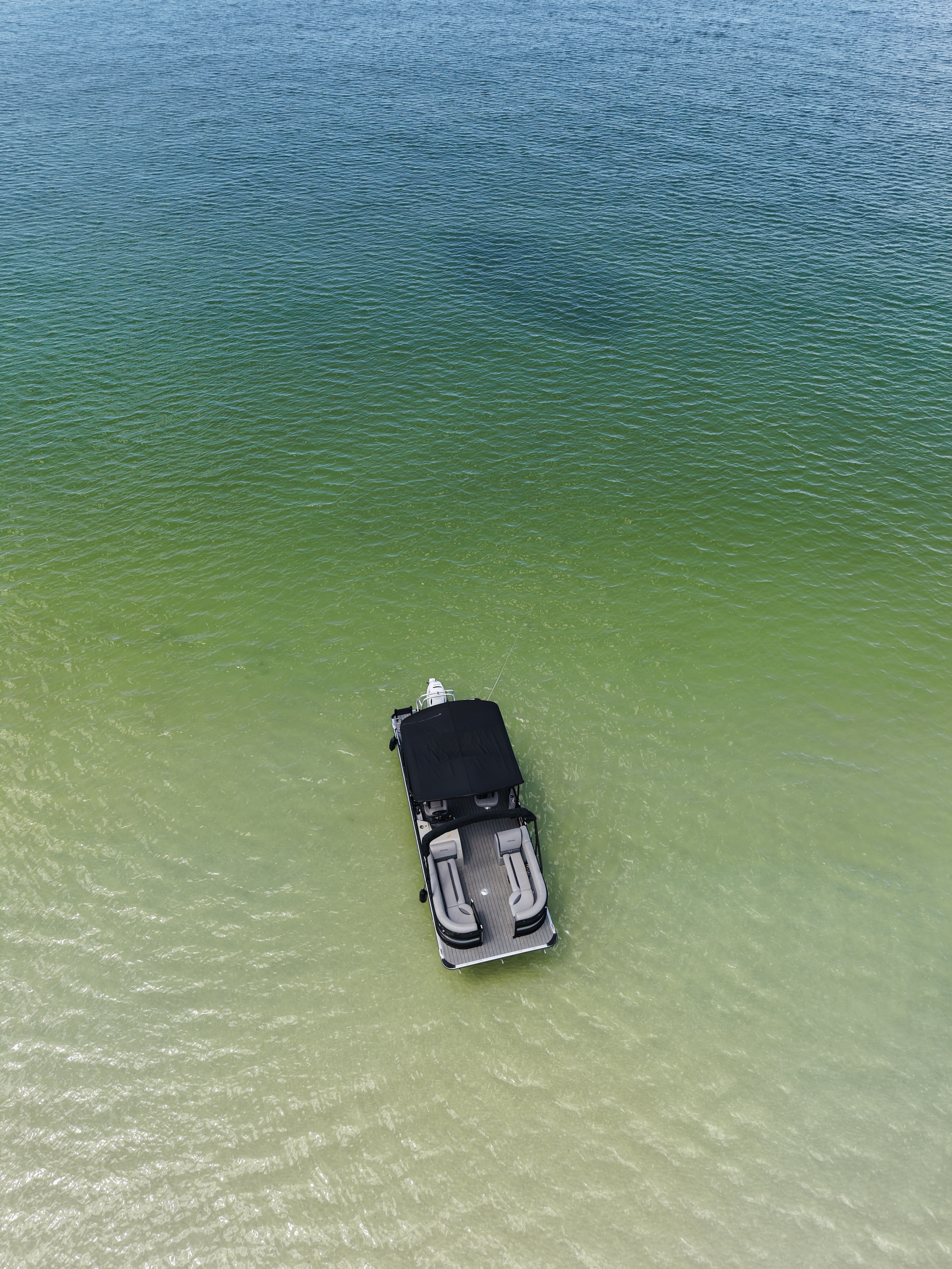 High aerial view of the Bentley tritoon over clear green water