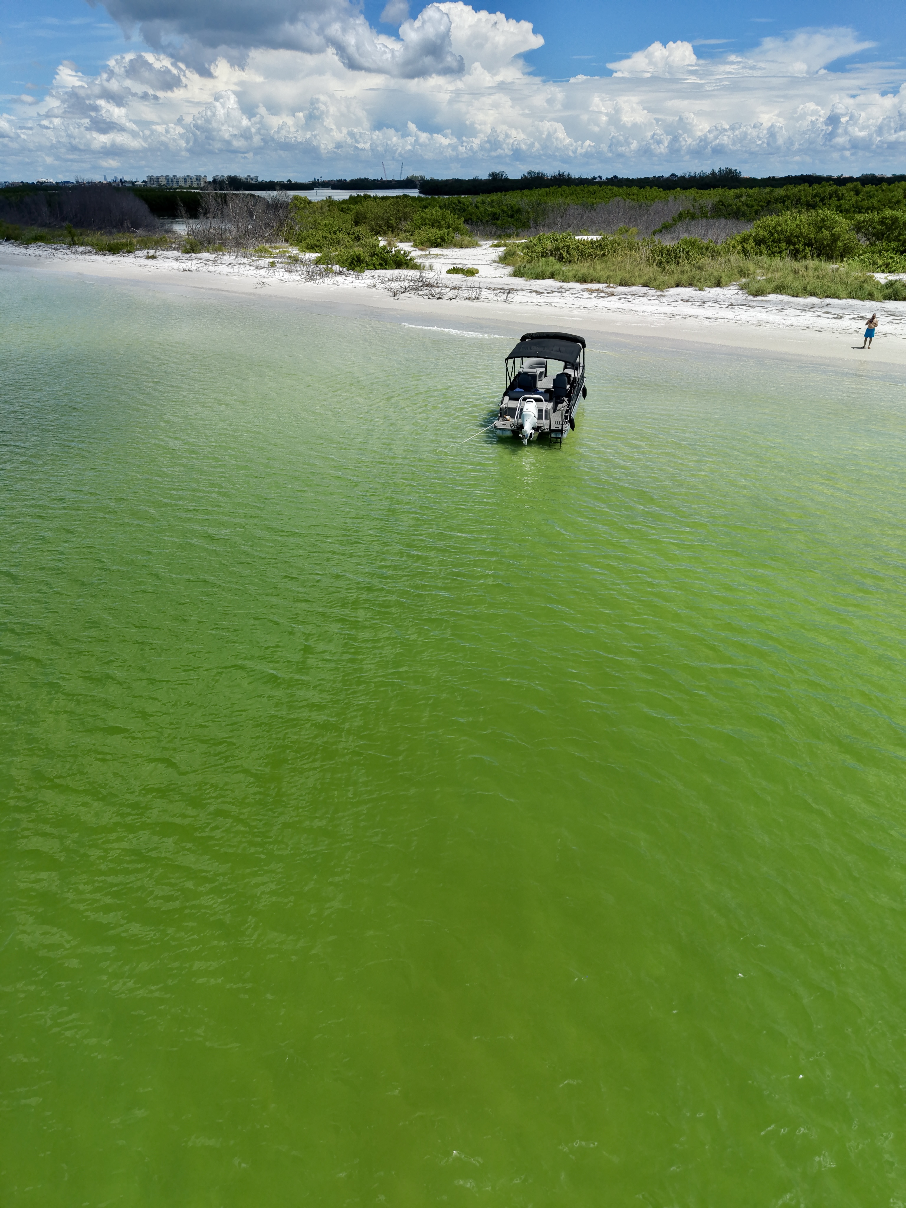 Drone view of the Bentley tritoon cruising near a bright sandy beach