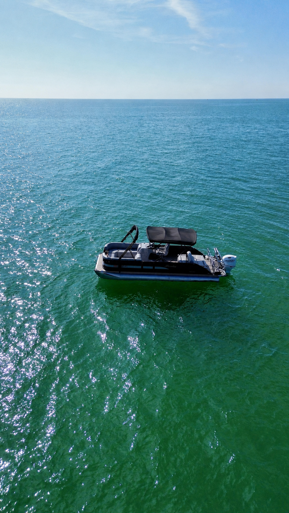 Black Bentley tritoon alone on clear turquoise Gulf water